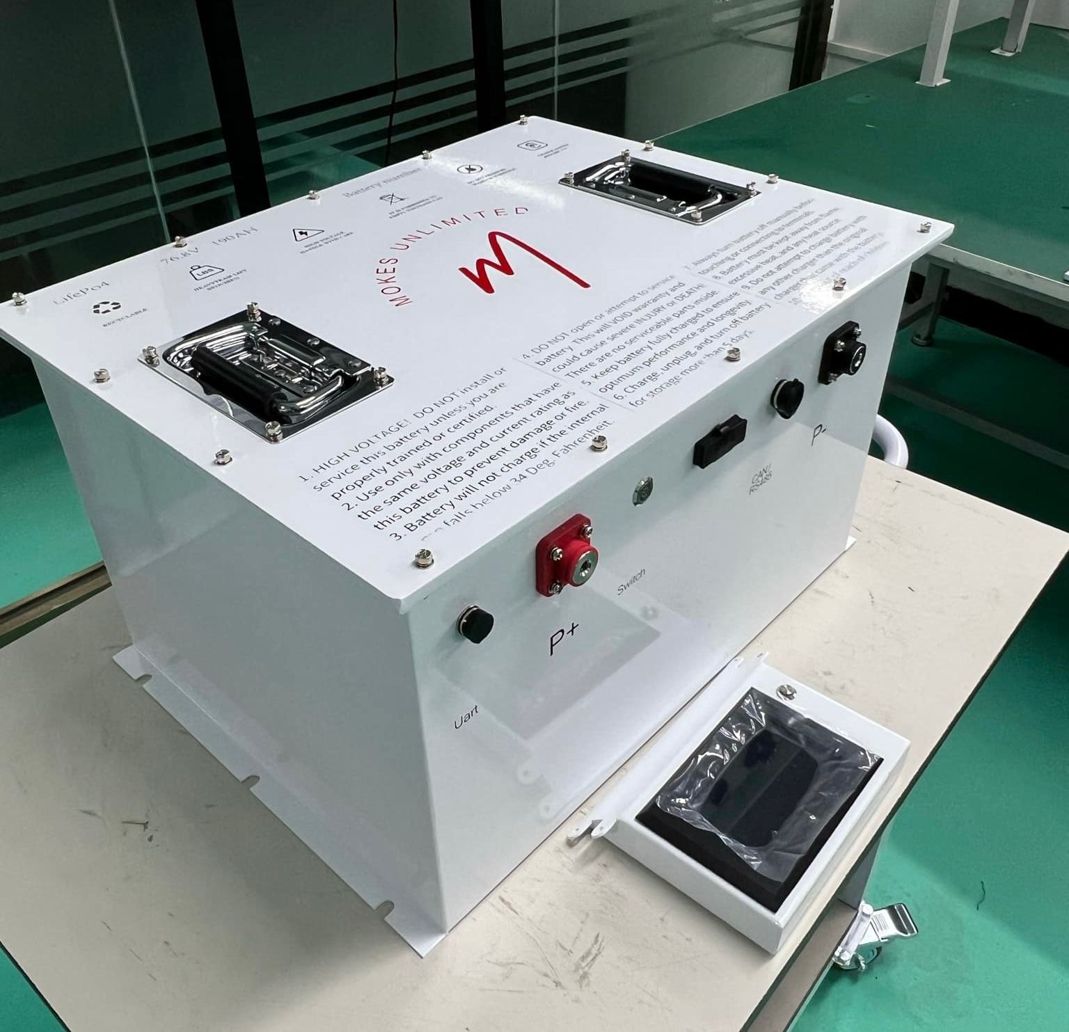 White rectangular electrical device with connectors, controls, and a small display on a table.