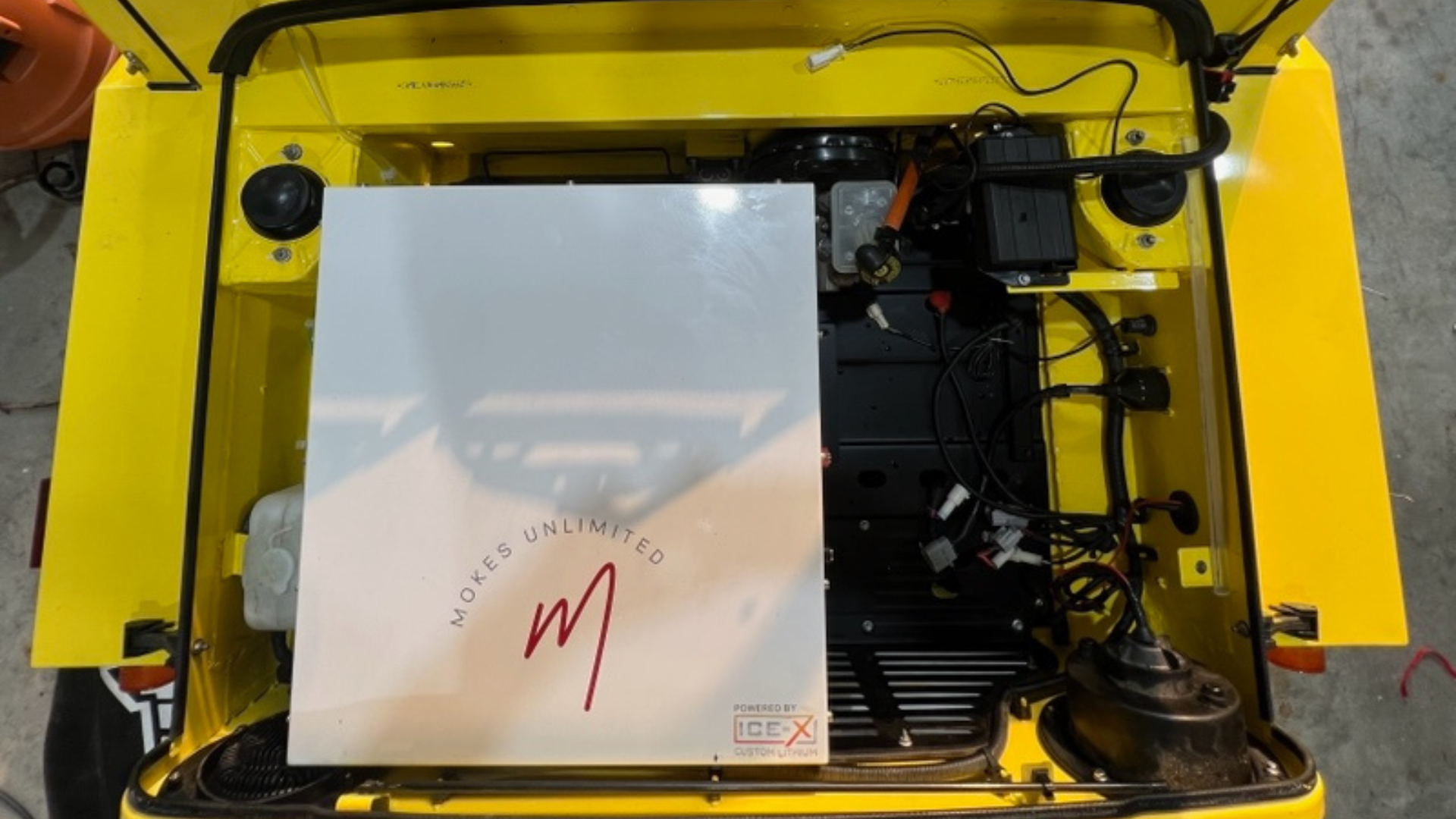 Yellow vehicle's open trunk with a white box labeled