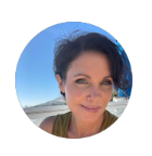 Close-up portrait of a woman outdoors with a blue sky and beach in the background