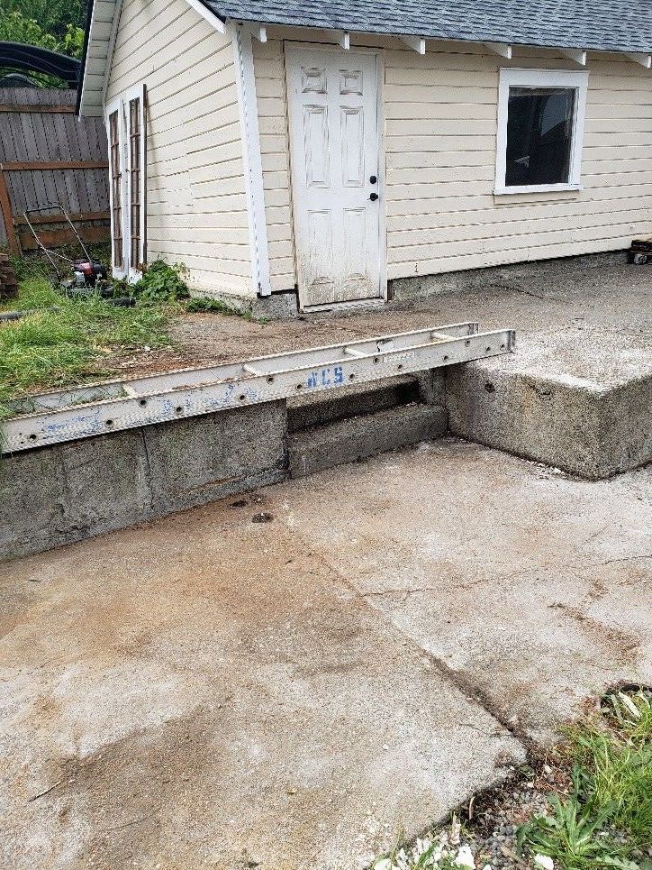A backyard with a wooden fence and concrete blocks in the grass.