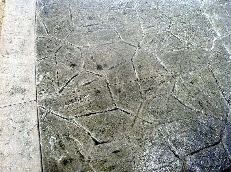 Stamped concrete patio with a stone-like texture. Gray with darker cracks.