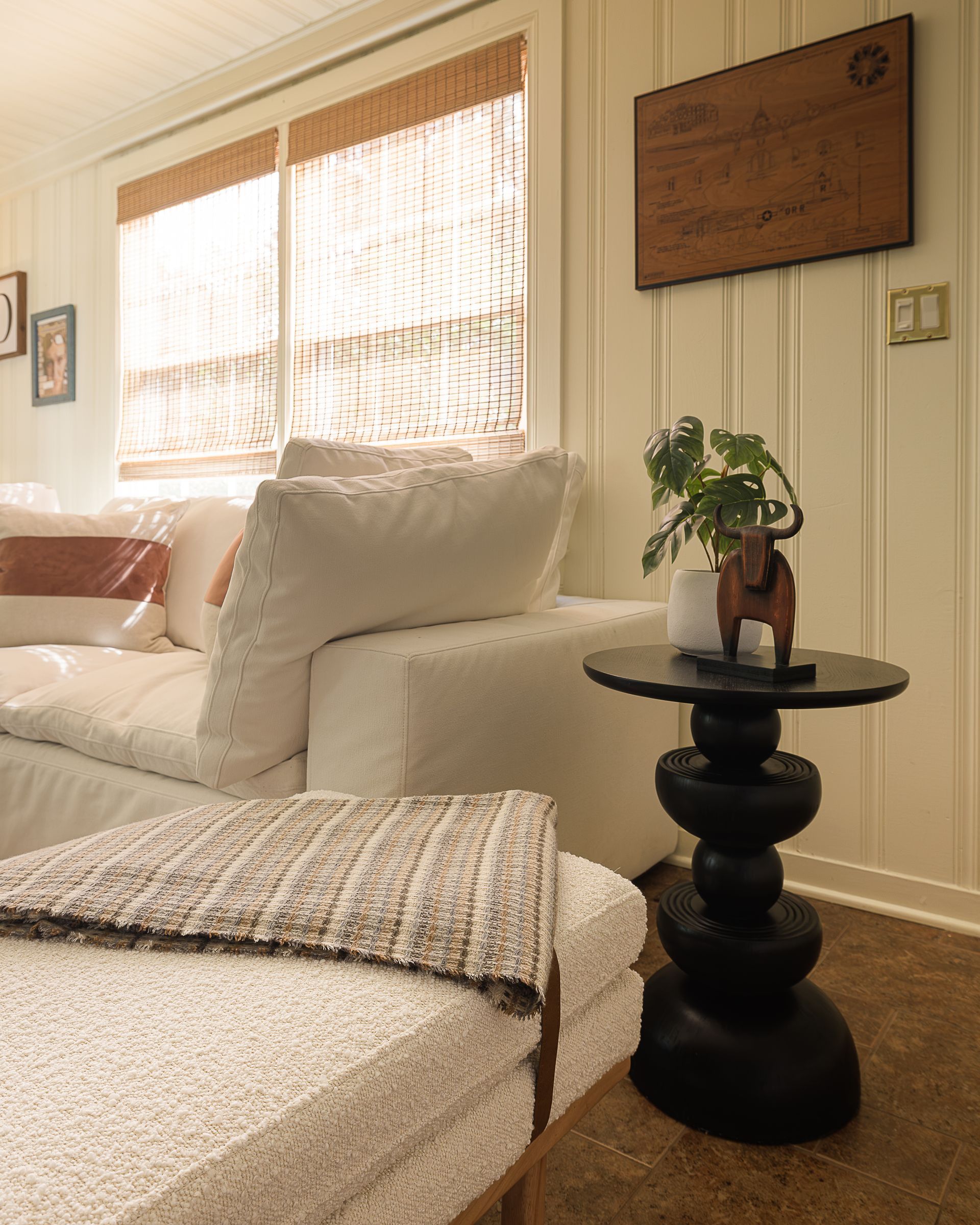 Den seating area with woven Roman shades and white paneled walls