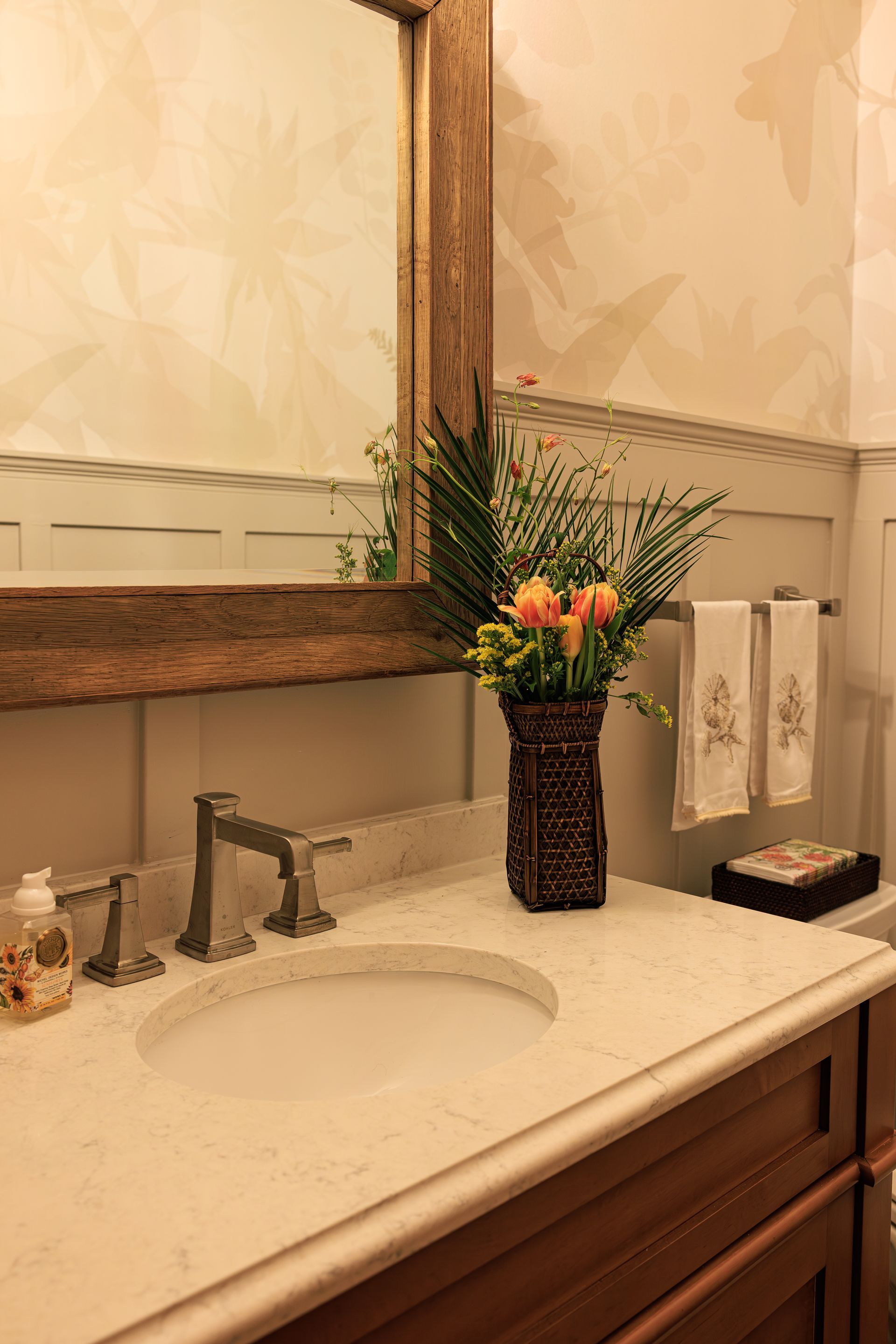 Soft botanical mural wallpaper above custom wainscoting