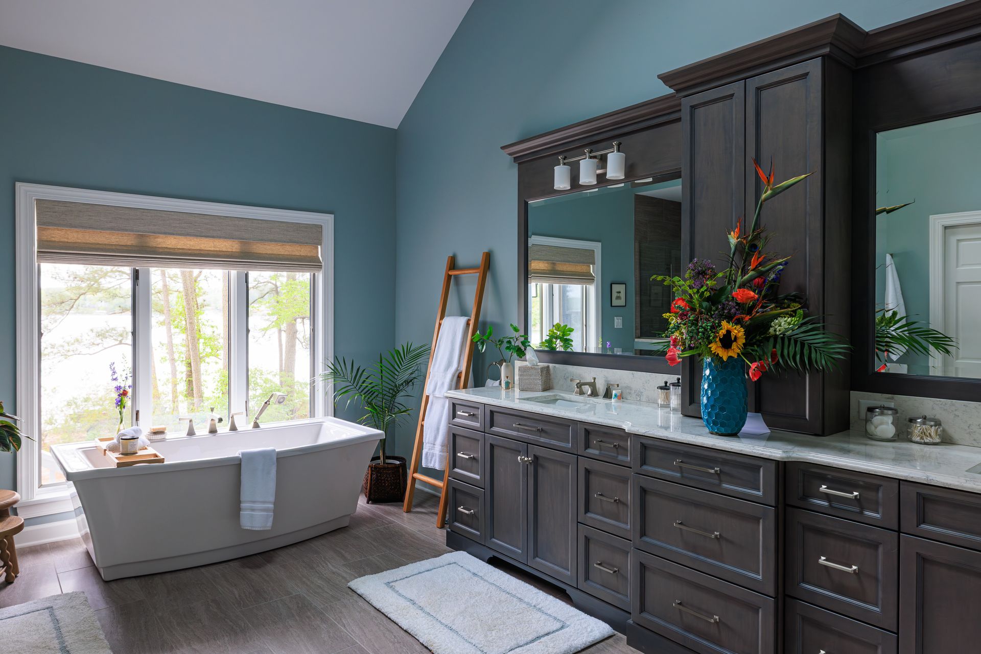 Primary bathroom with freestanding tub, blue walls, dark wood vanity, and Roman shade
