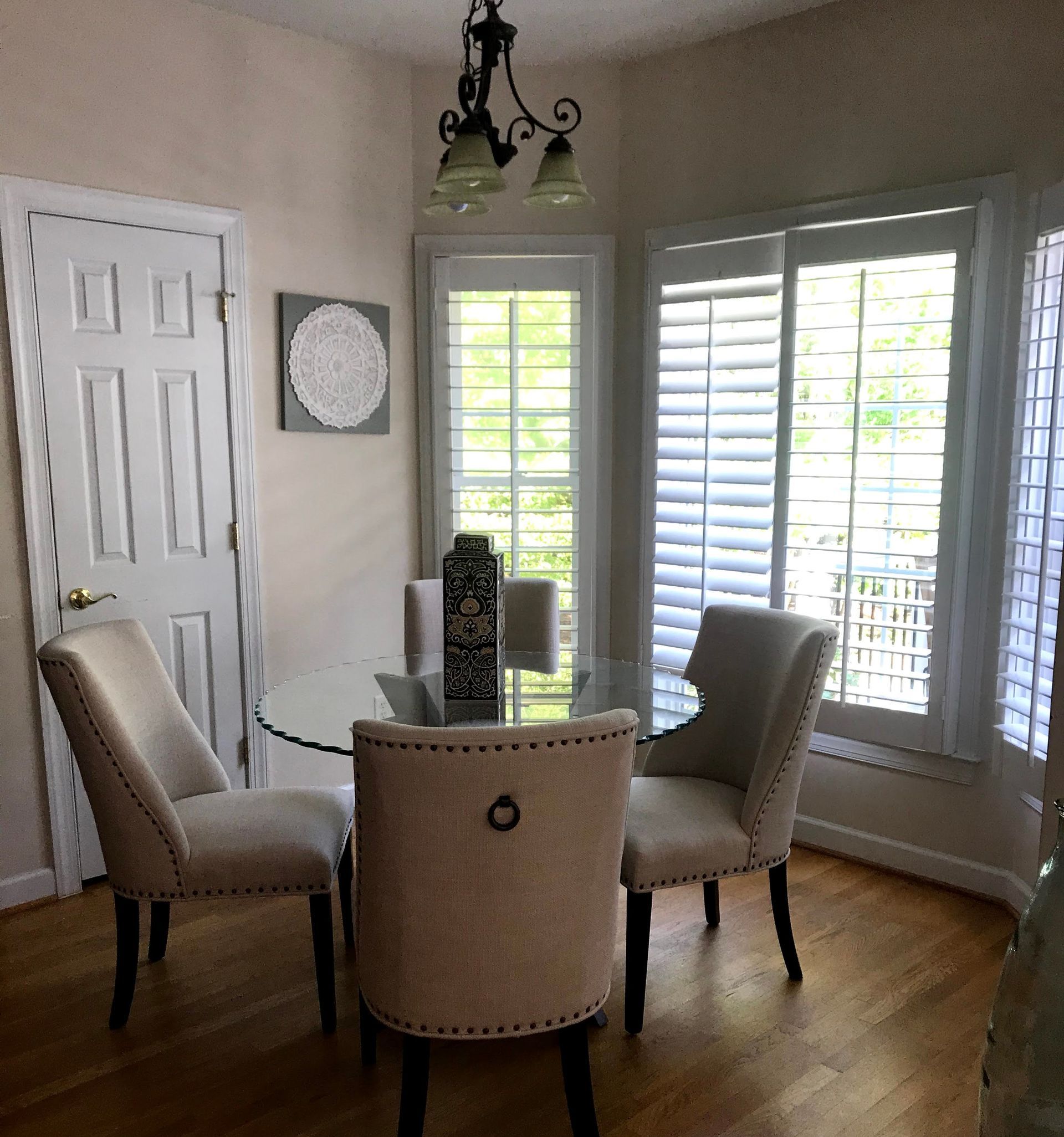 Neutral room with plantation shutters, chandelier, and framed mirror