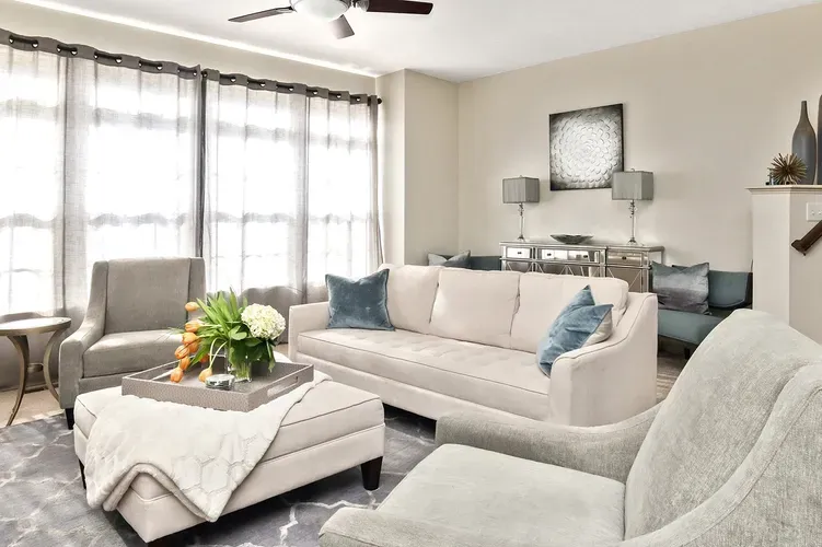 Bright living room with neutral sectional, coffee table, and soft window treatments