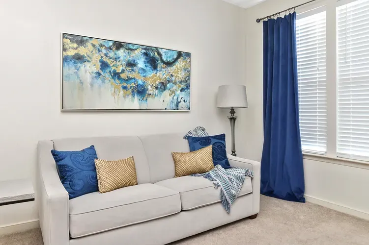 Sitting room with white sofa, blue drapery, and abstract wall art