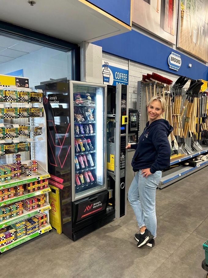 Woman posing in a store aisle beside a candy display and refrigerated case