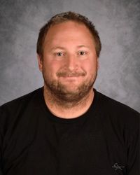 Studio portrait of a smiling person in a black shirt against a gray background