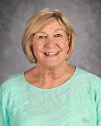 Smiling woman in a mint green top against a gray studio backdrop