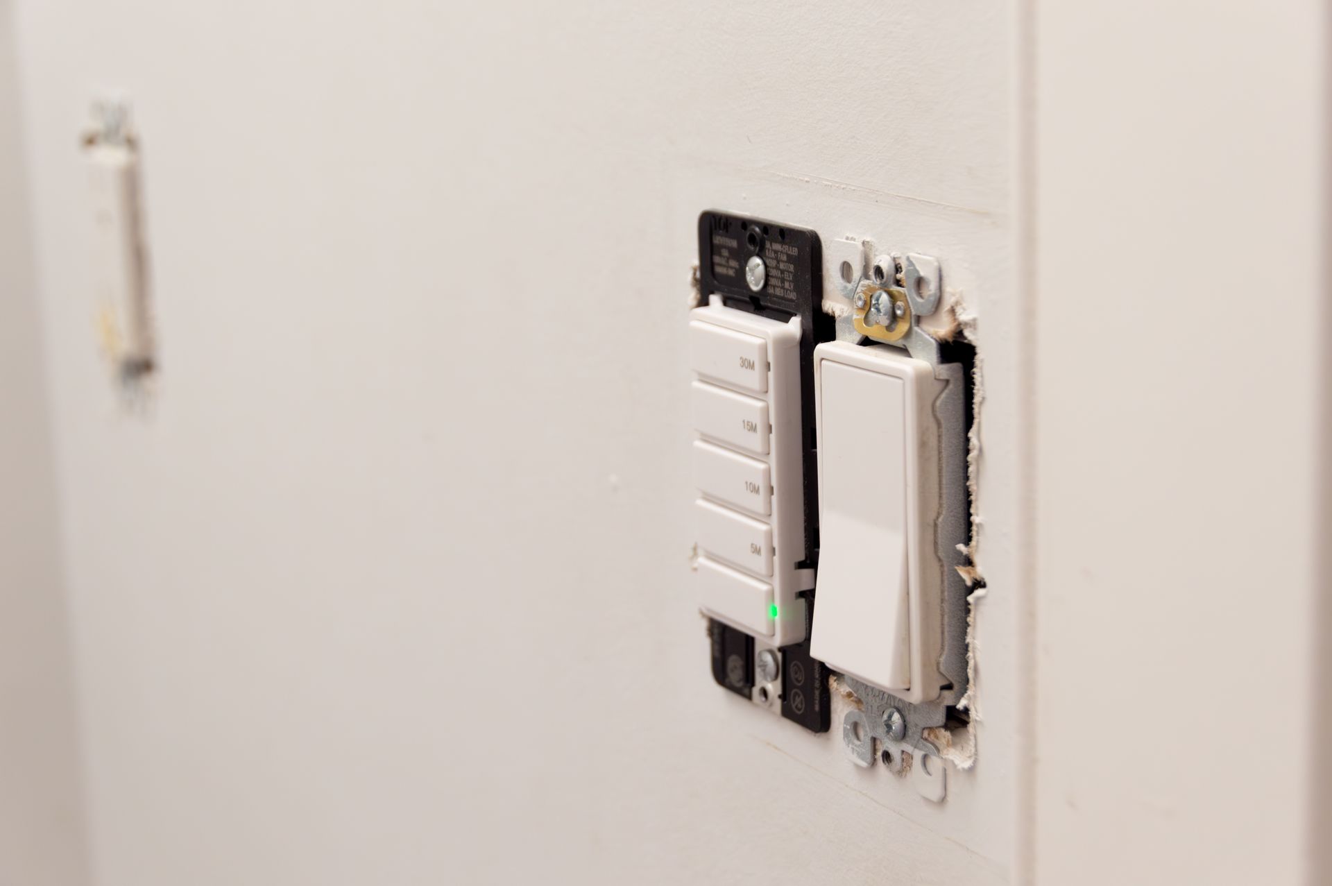 Partially installed white light switches and outlet on a wall, with exposed wiring.