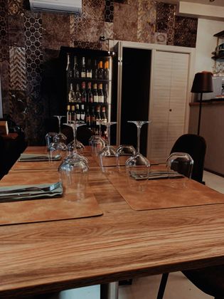 Un tavolo di legno con sopra dei bicchieri da vino in un ristorante.