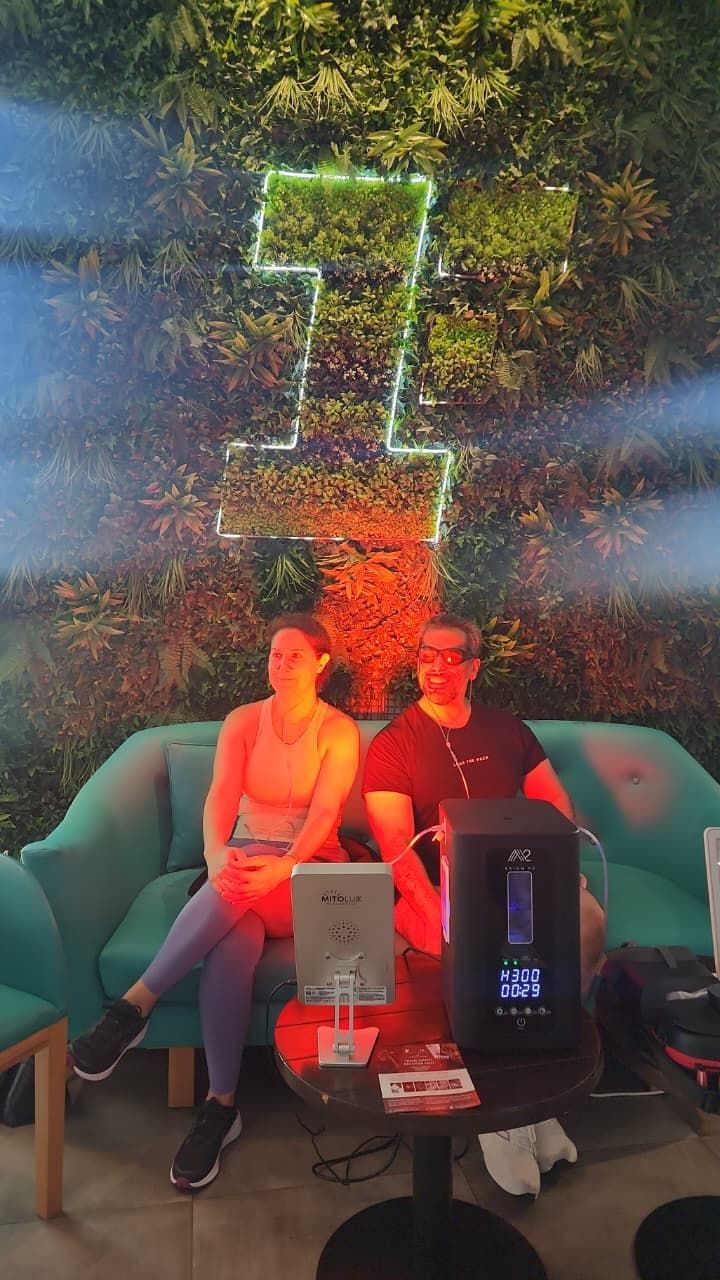 Two people sit on a couch beside glowing electronics under colorful lights and falling confetti.