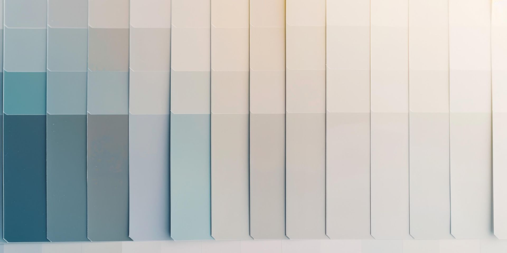 Abstract close-up of vertical glass panels in muted blue, gray, and beige tones