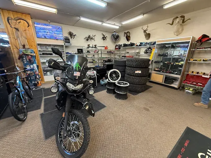 Motorcycle inside a shop, surrounded by tires, equipment, and mounted animal skulls.