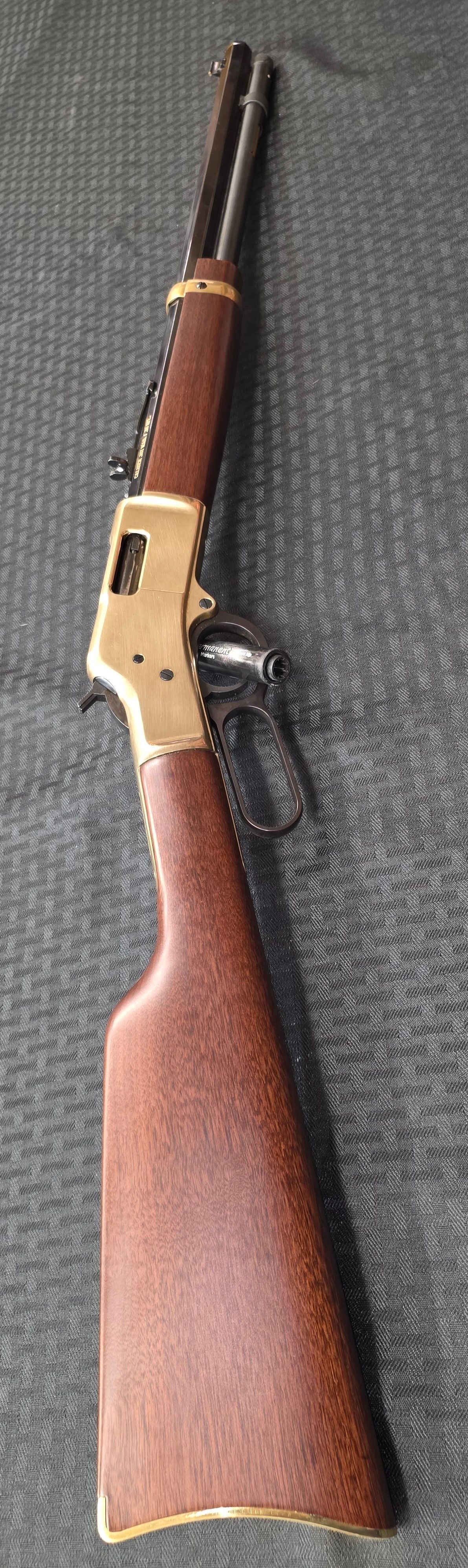 A tan CZ Scorpion EVO 3 S1 submachine gun featuring a red trigger, angled foregrip, and mounted optic on a textured surface.