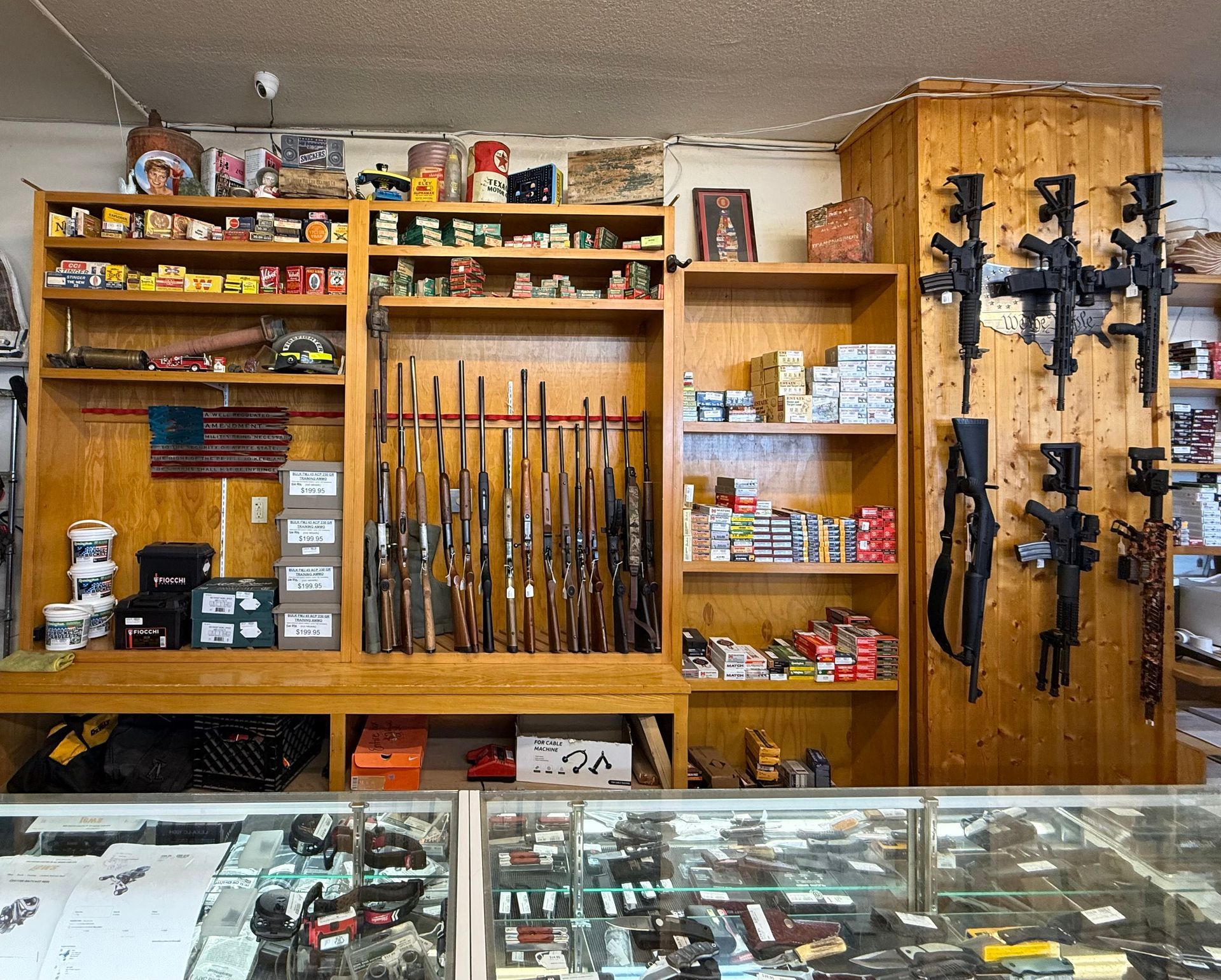 Interior of a gun shop with firearms displayed on shelves and hanging on walls; ammunition and accessories are also visible.