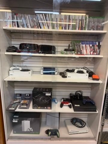 Display case with video games, controllers, and consoles for sale.