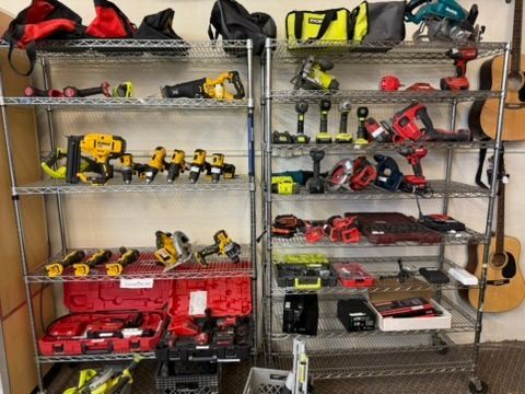 Shelves filled with power tools, including drills, saws, and nail guns, mostly red, yellow, and black.