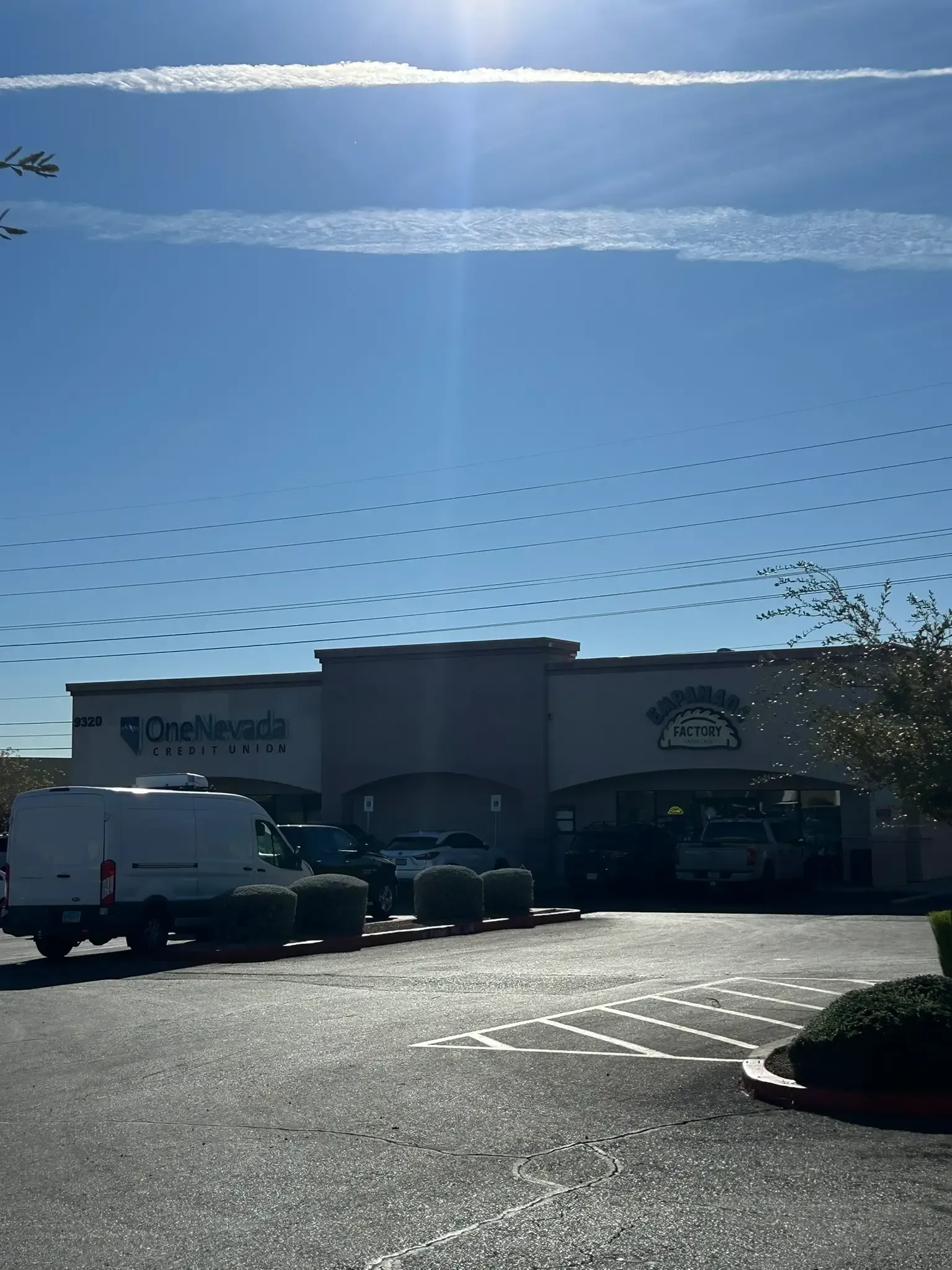 Big retail store exterior with parked vehicles under a clear blue sky.
