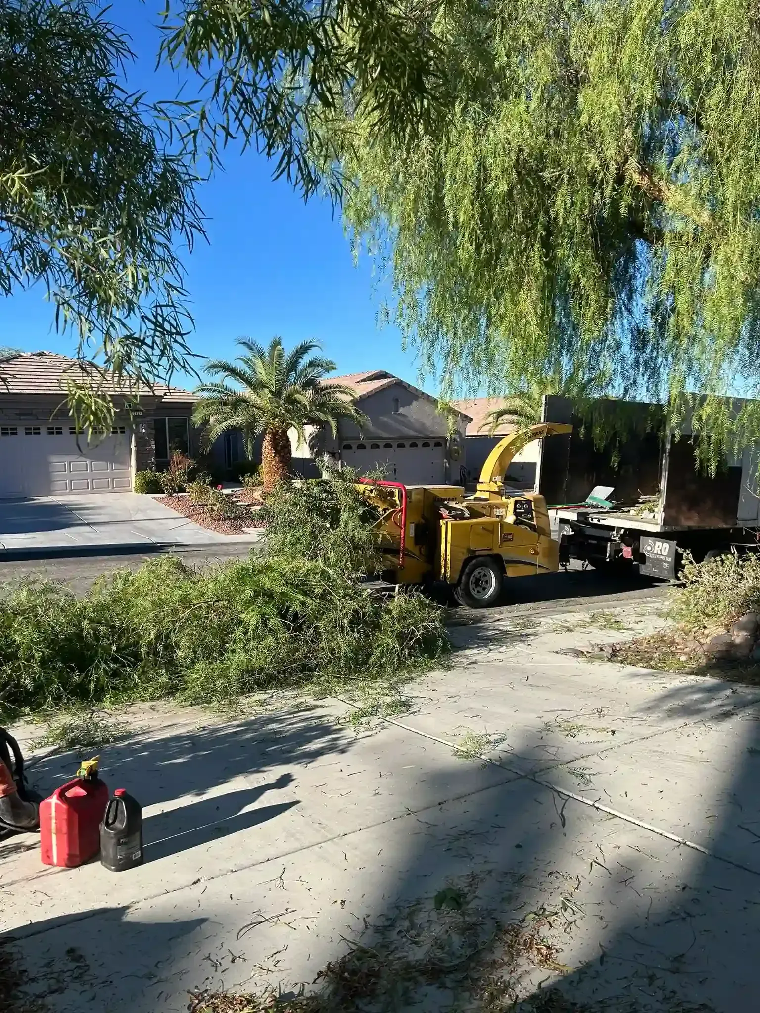 Sidewalk beside a stucco wall with trees, parked van, and construction cones under a blue sky