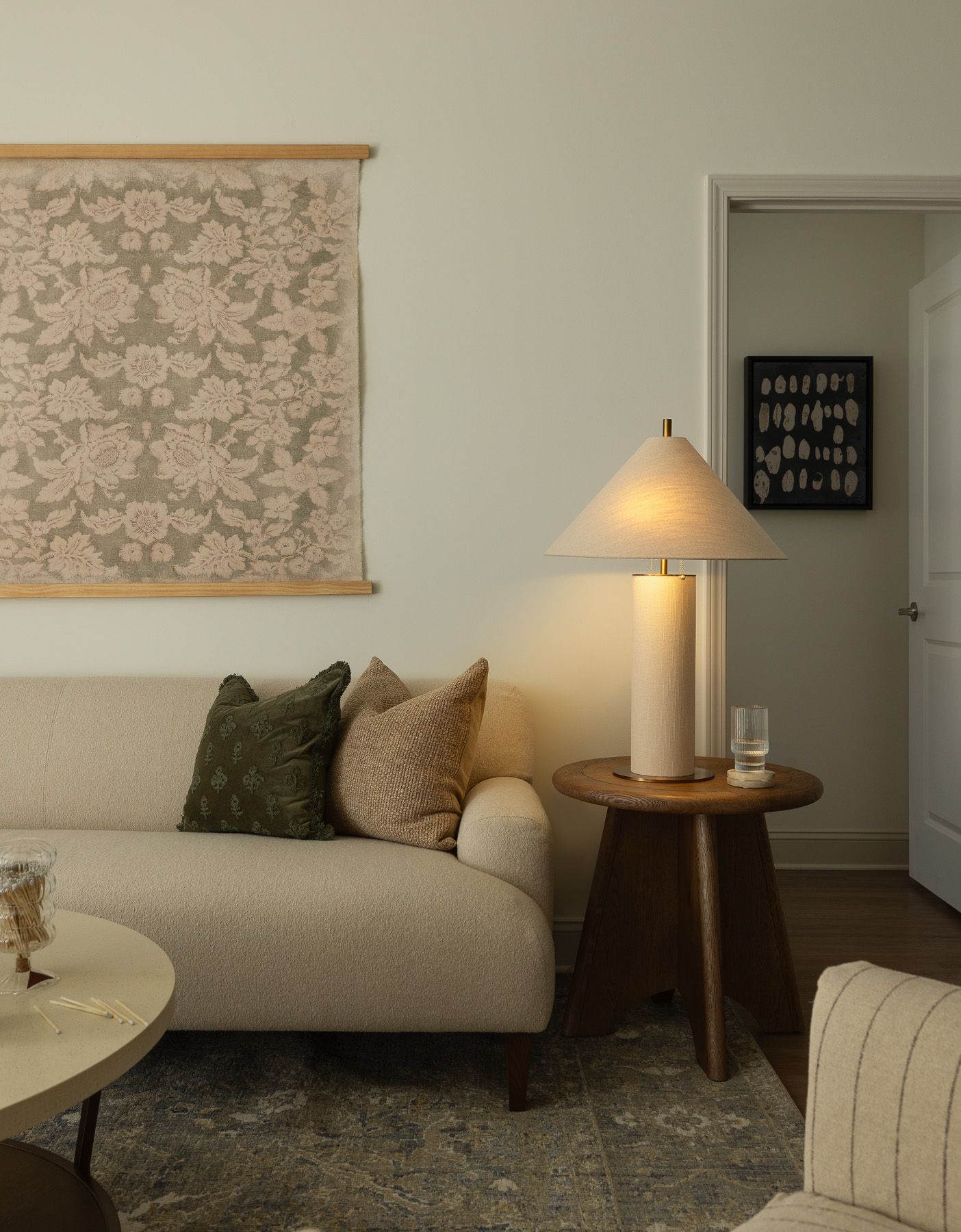 Living room with sofa, lamp on side table, and floral artwork.