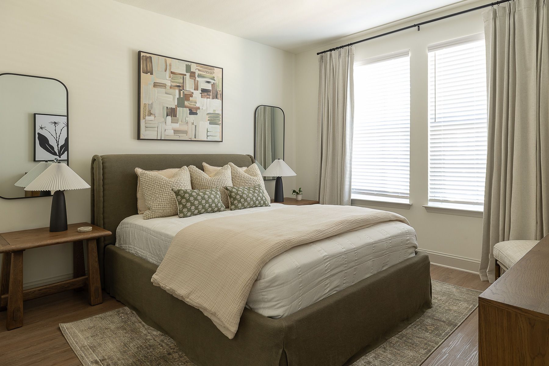 Bedroom with bed, art, mirrors, and window with curtains; neutral color scheme.
