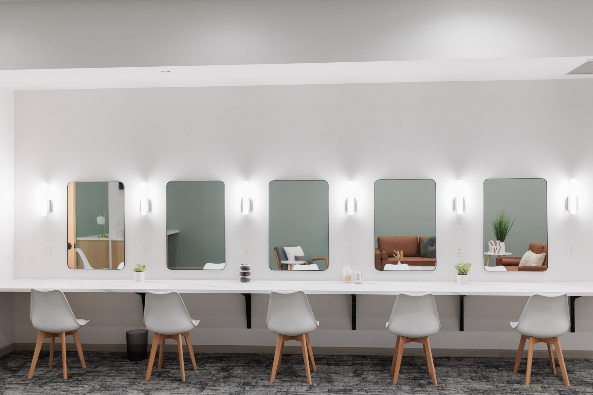 Bright salon interior with five mirrors, styling stations, and white chairs along a long counter.