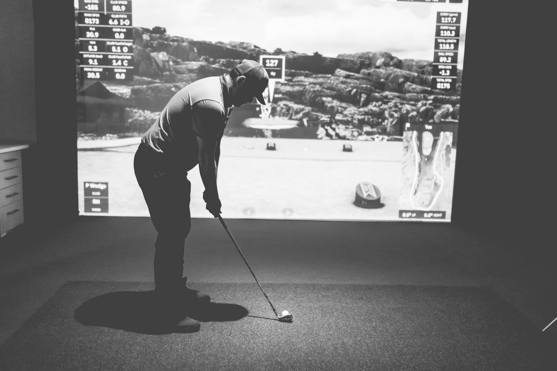 Person putting on an indoor golf simulator, aiming at a projected course scene.