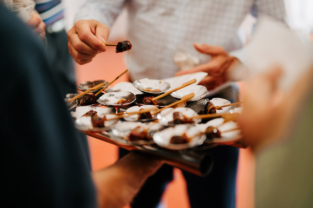 Hands serving chocolate desserts on a tray at a gathering