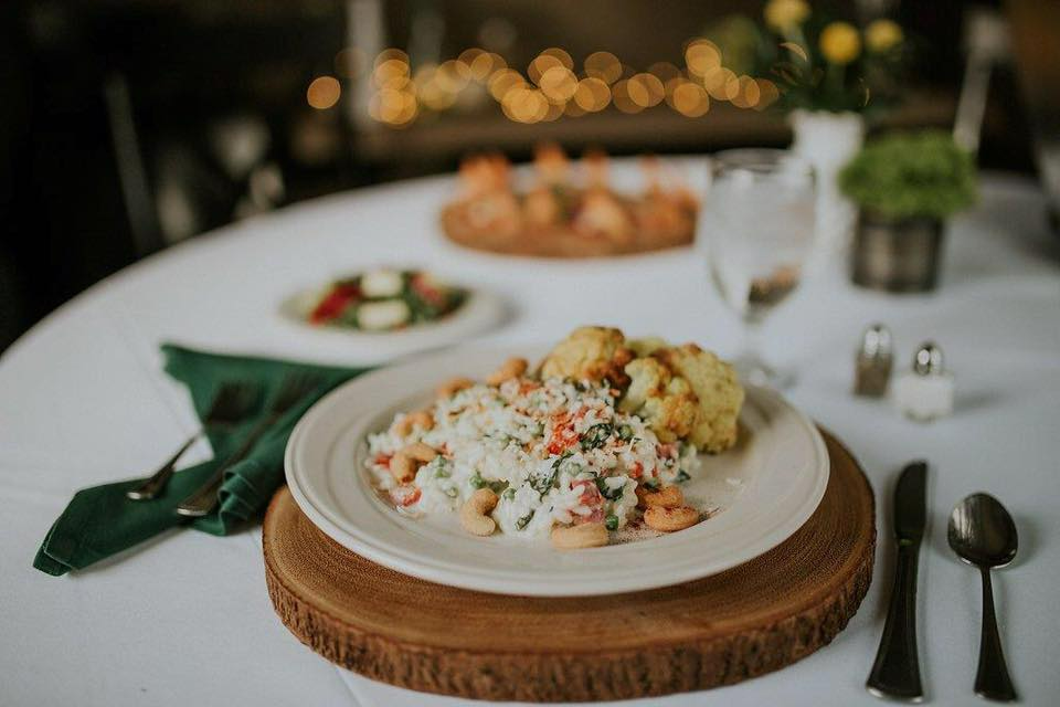 Elegant table setting with a plated salad, woven charger, and blurred warm lights in the background