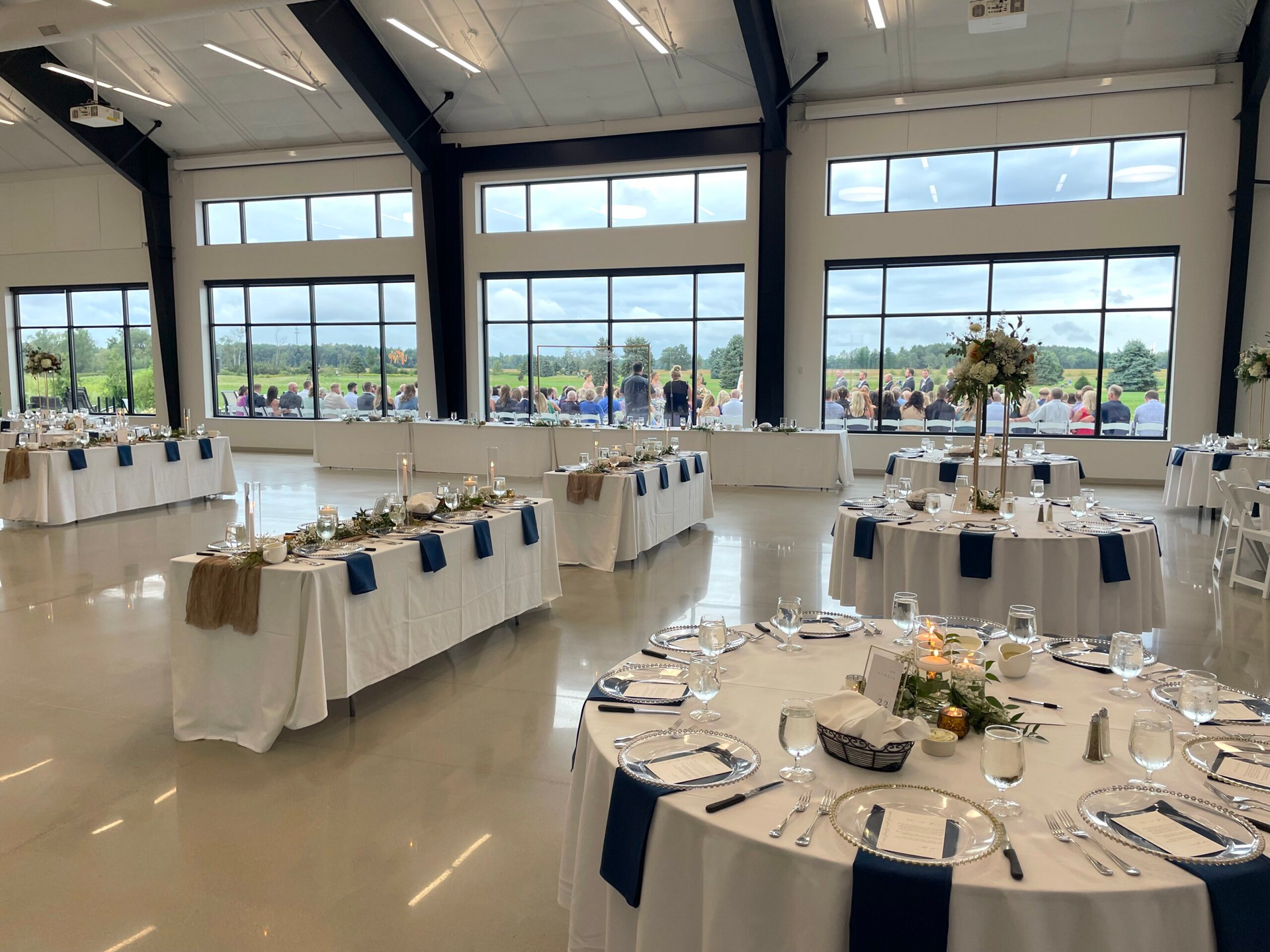 Banquet hall with round tables, white tablecloths, and large windows overlooking a scenic view