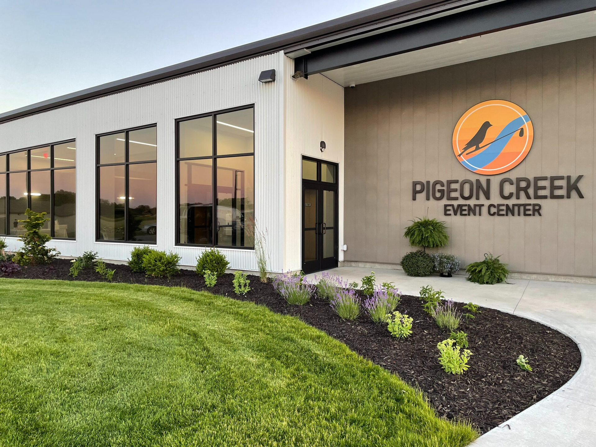 Pigeon Creek Event Center exterior with white siding, large windows, and landscaped entrance