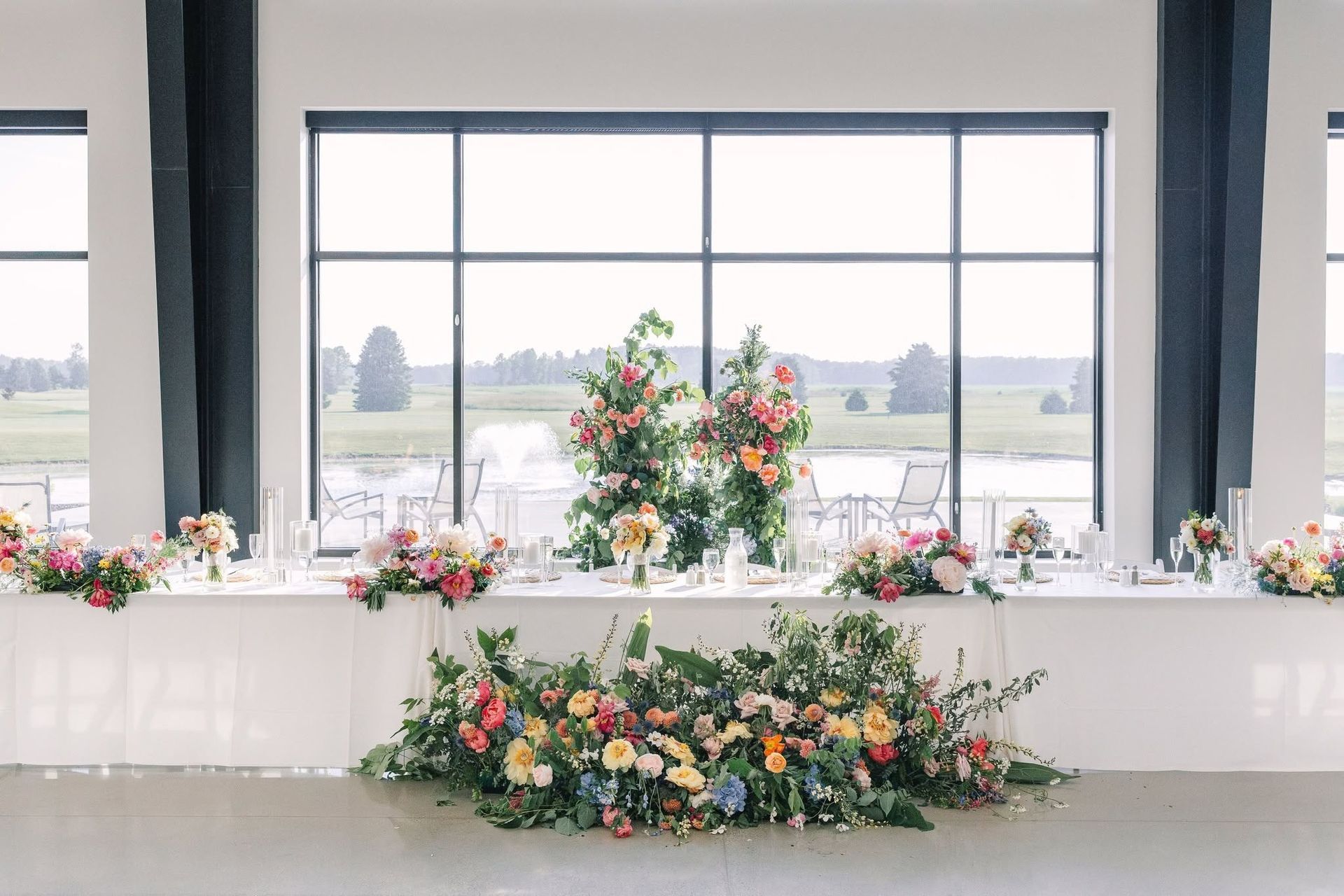 Floral wedding altar with white drapery and a large window overlooking a field