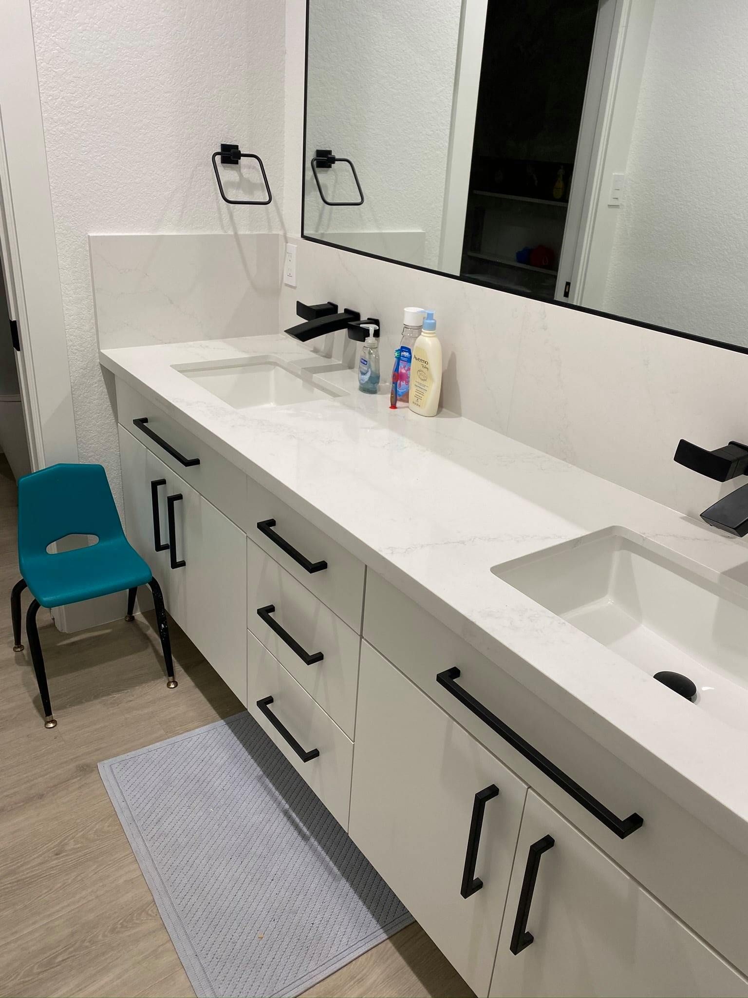 Modern bathroom vanity with double sinks, mirror, soap dispenser, and teal stool