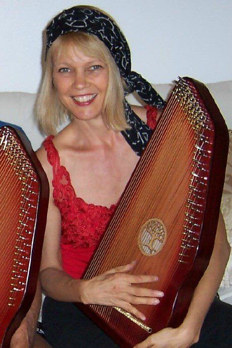A woman in a red top is holding a harp