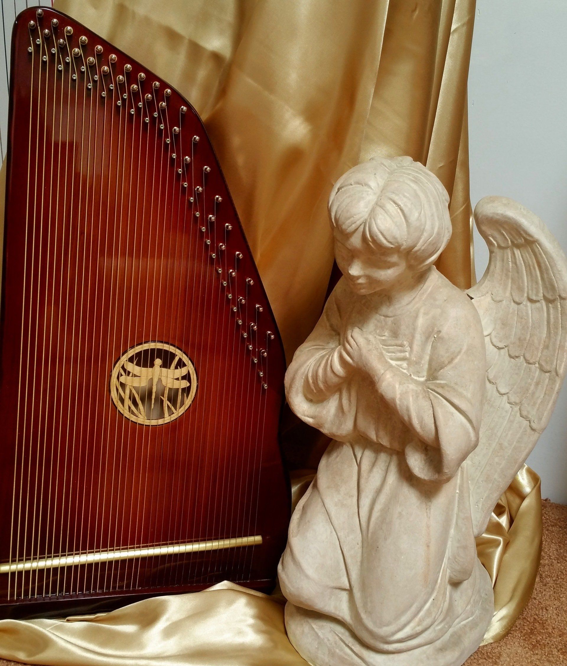 A statue of an angel kneeling next to a harp