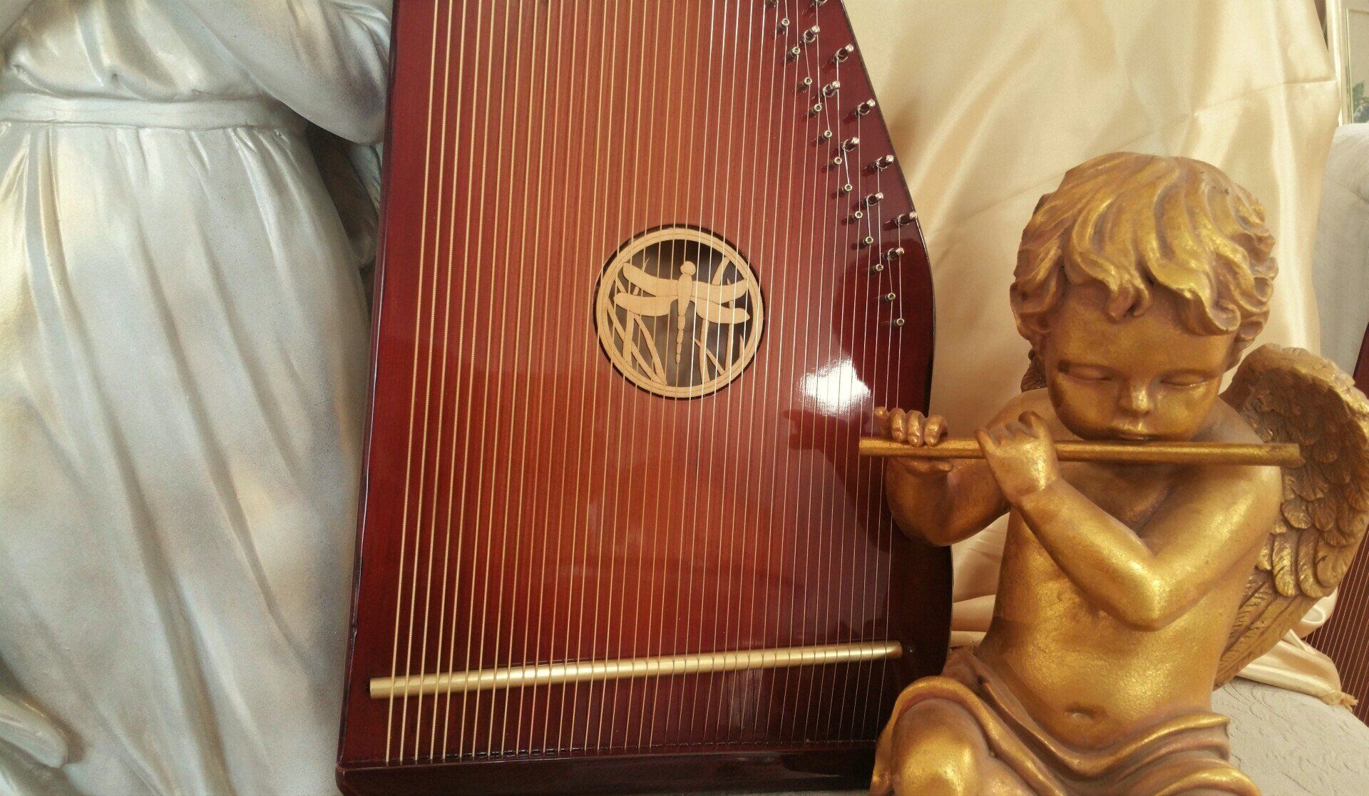 A statue of a cherub playing a flute next to a harp