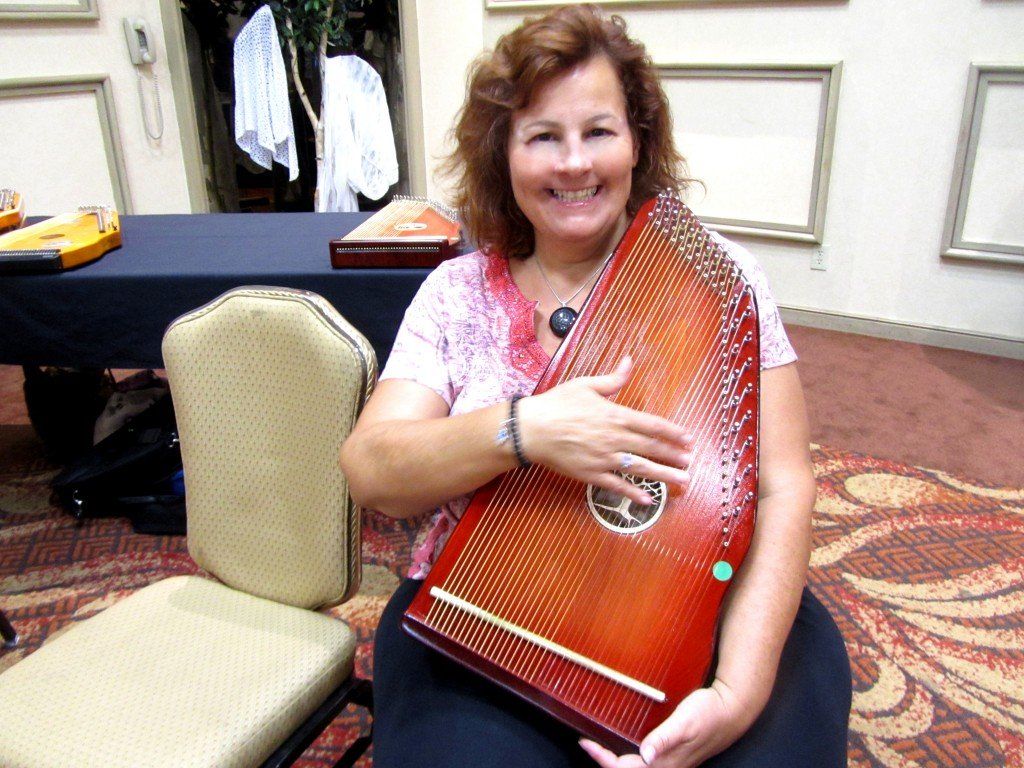 A woman is sitting in a chair holding a harp and smiling