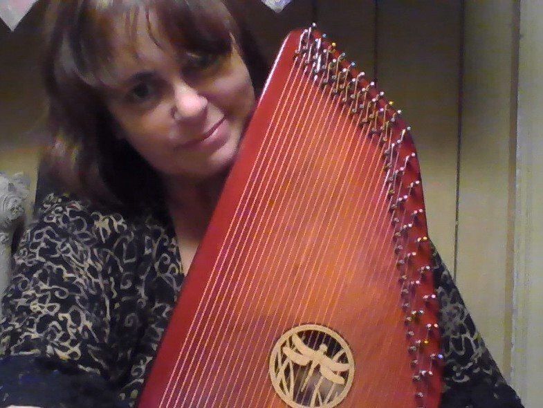 A woman is holding a harp with a dragonfly on it