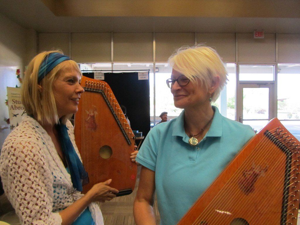 Two women are holding harps and talking to each other