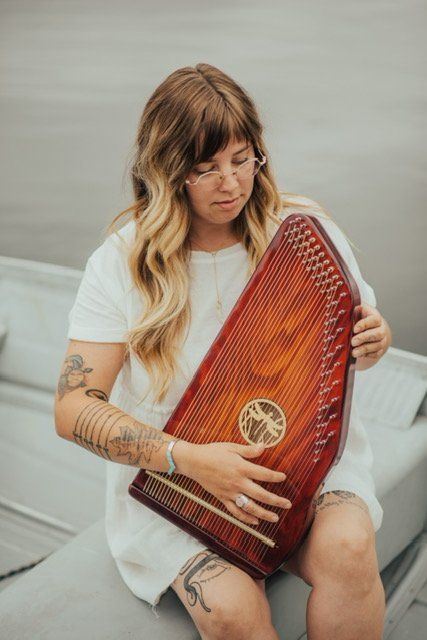 A woman is sitting on a boat playing a harp.