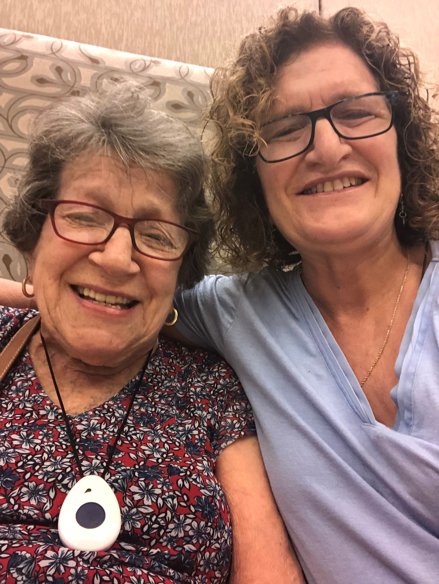 Two women are posing for a picture together and smiling . one of the women is wearing glasses.