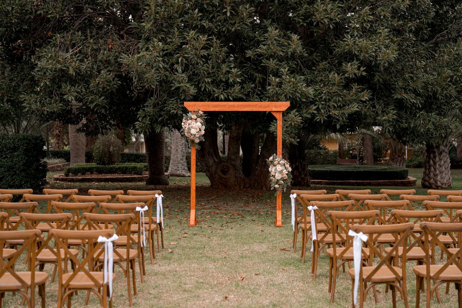 Outdoor wedding setup with wooden chairs.