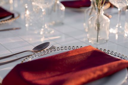 Elegant table setting with red napkins, silverware, and glassware.
