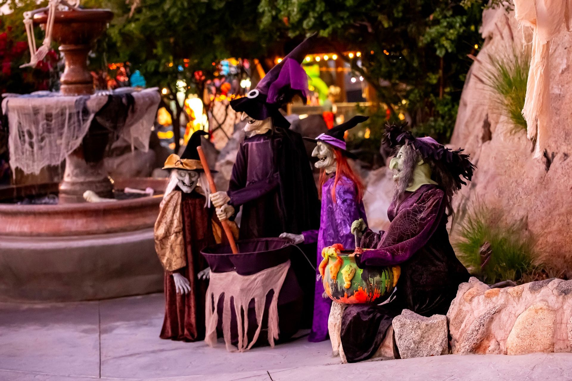 People in colorful costumes by a fountain at a nighttime outdoor event
