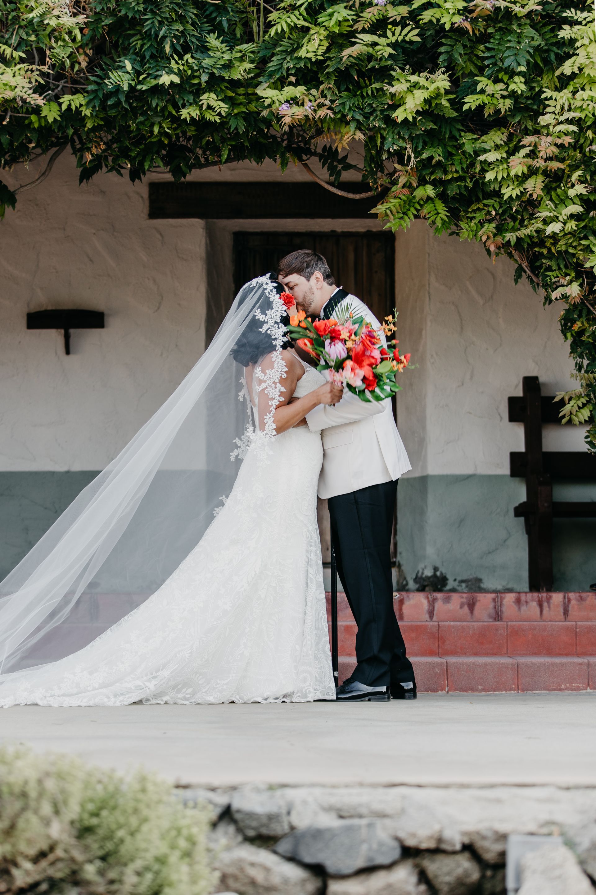 Photo of a couple's first kiss at their wedding ceremony on the steps of the Hacienda from the set of