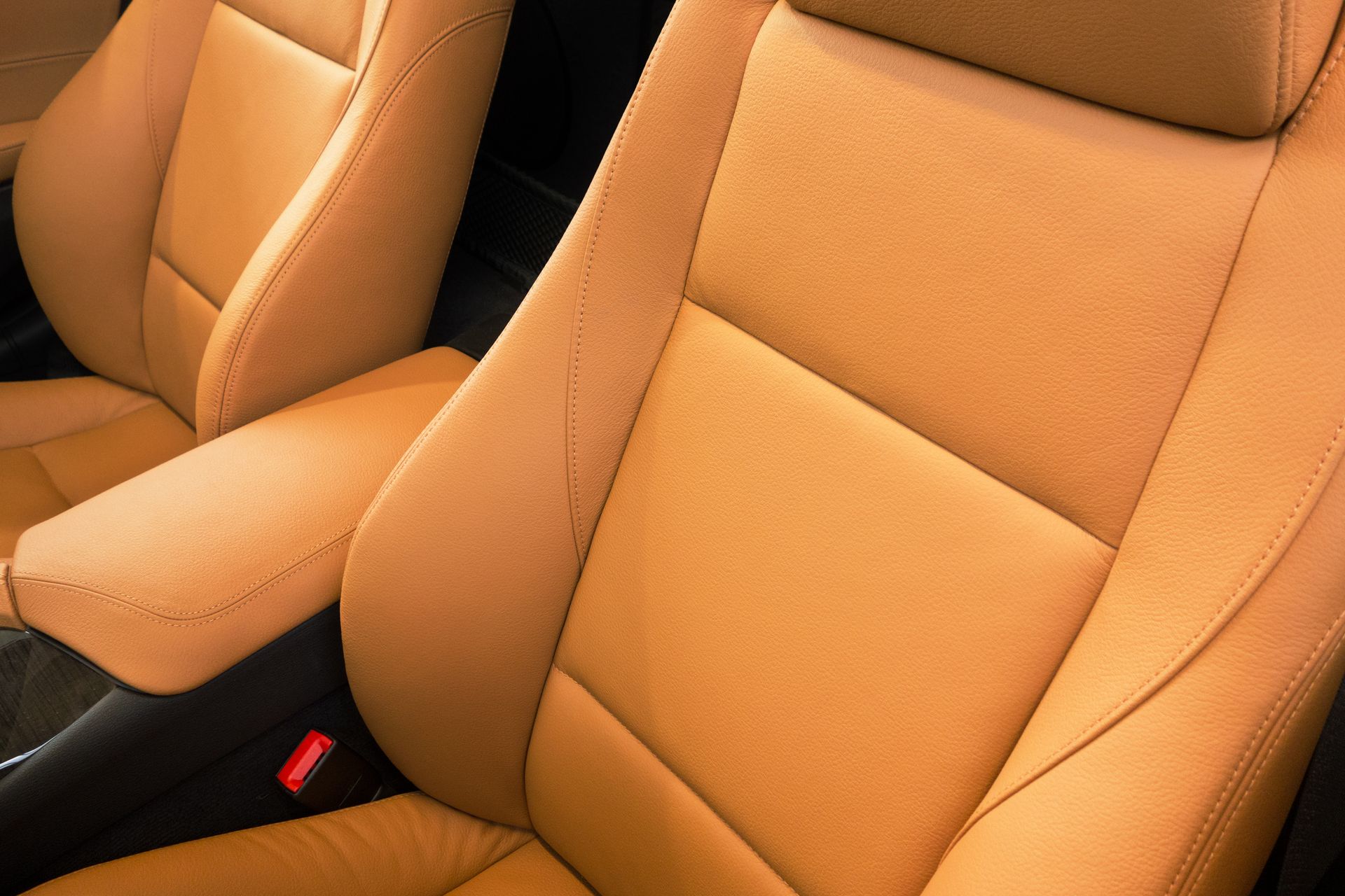 Tan leather car seats with headrests and armrest.