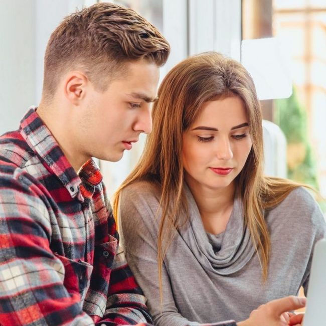 Two people sitting together, looking at a tablet in a bright room