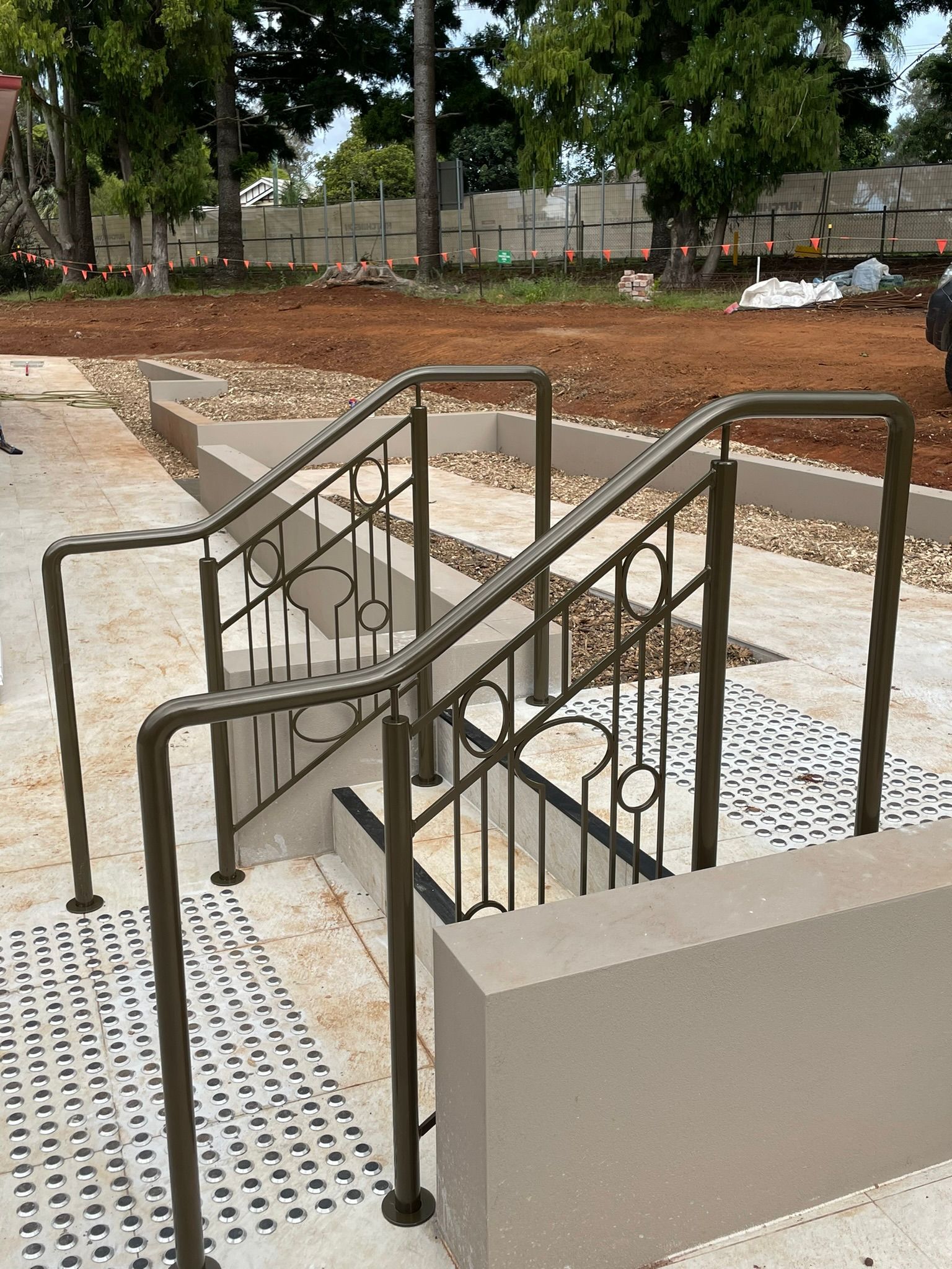 A set of stairs with a wrought iron railing leading up to a dirt field.
